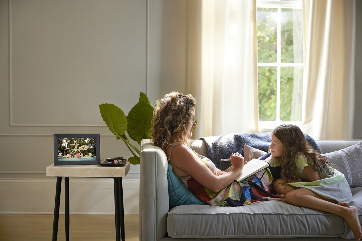 Dark Aura Carver landscape frame on a side table beside a family sitting on a sofa