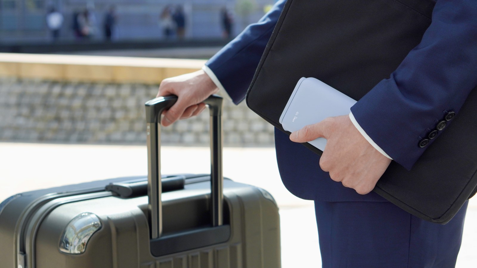 Traveler holding a GL.iNet Beryl AX GL-MT3000 beside luggage.