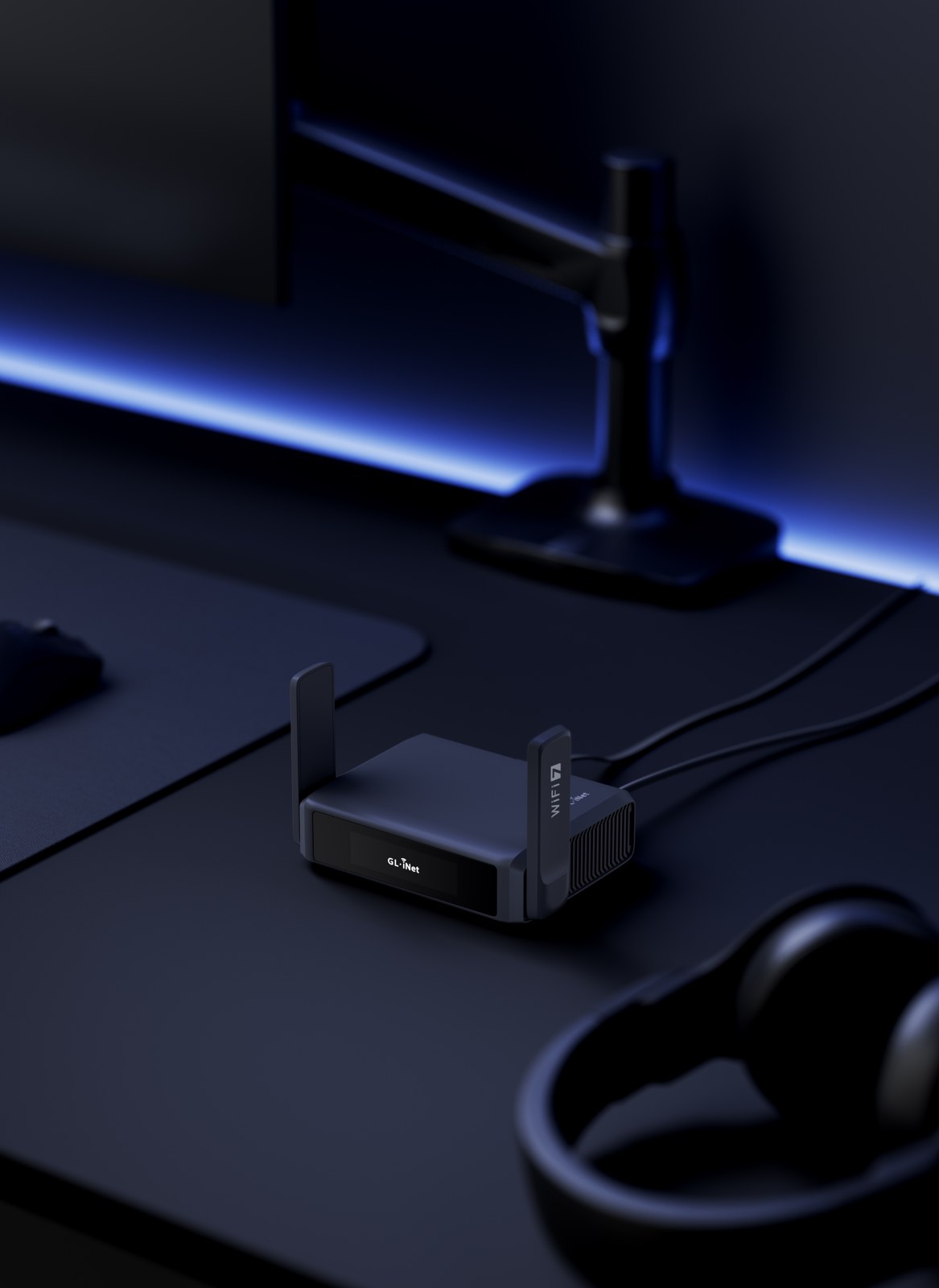 GL.iNet Slate 7 GL-BE3600 beside a monitor with Ethernet cables.