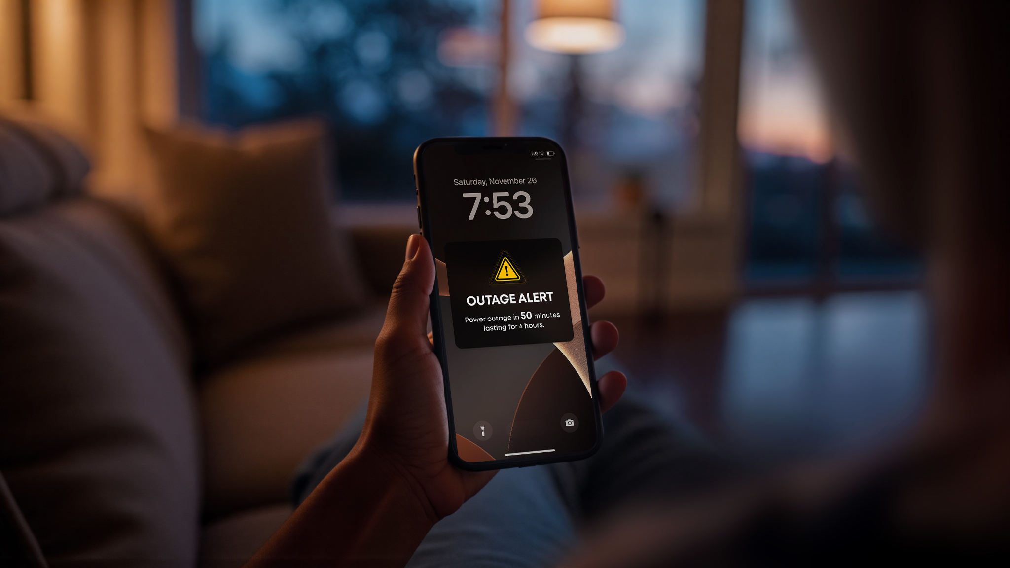 Manufacturer illustration of a person holding a phone displaying an example outage notice in a dim room.